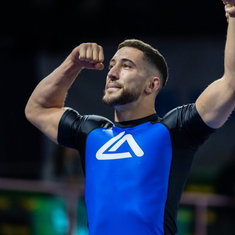 Blue belt male Roger Gracie competitor having his hand raised after winning a match in competition.